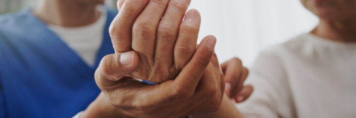 Physical therapist examining a mature woman’s hand during therapy.